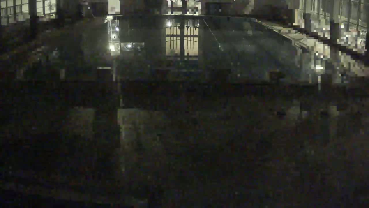 A dark, nighttime view of a pool reflecting interior lighting.