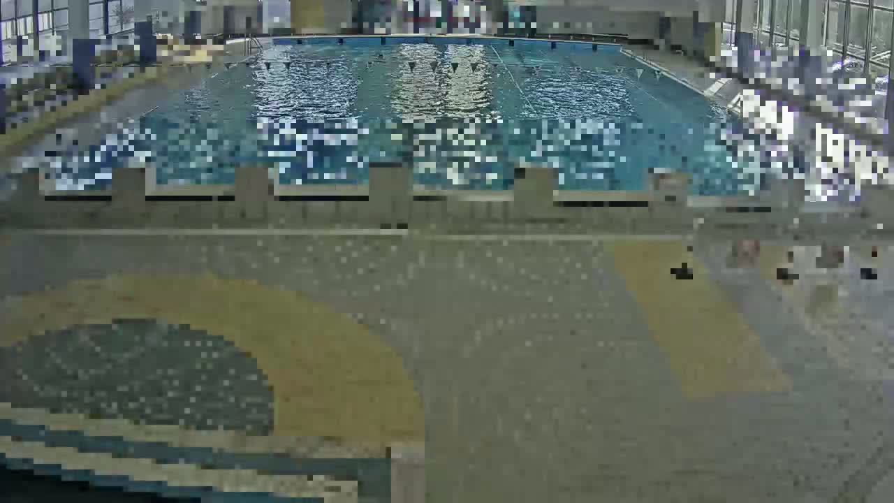 An indoor swimming pool with light-colored tiled floors and walls, and a large body of water.