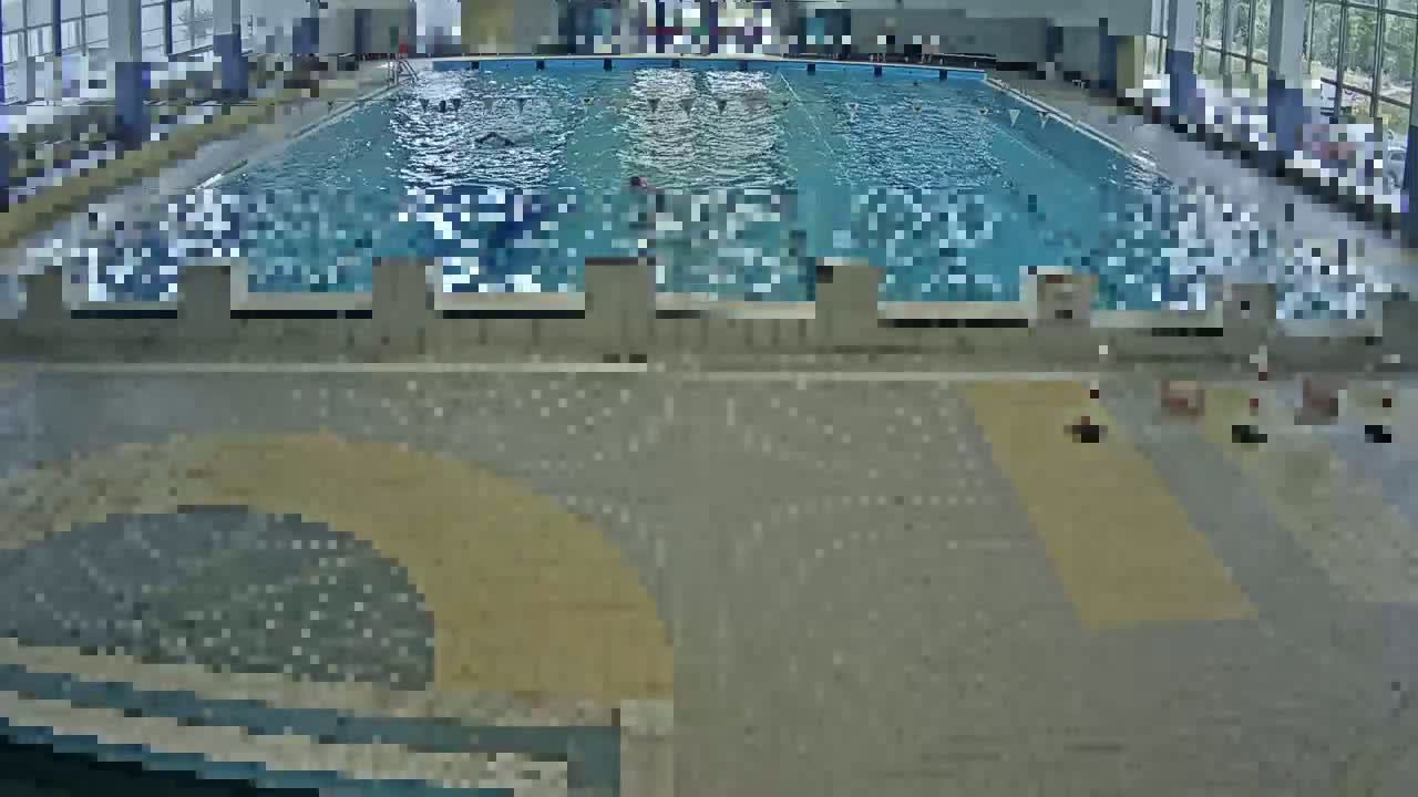 An indoor swimming pool with several people swimming in it.