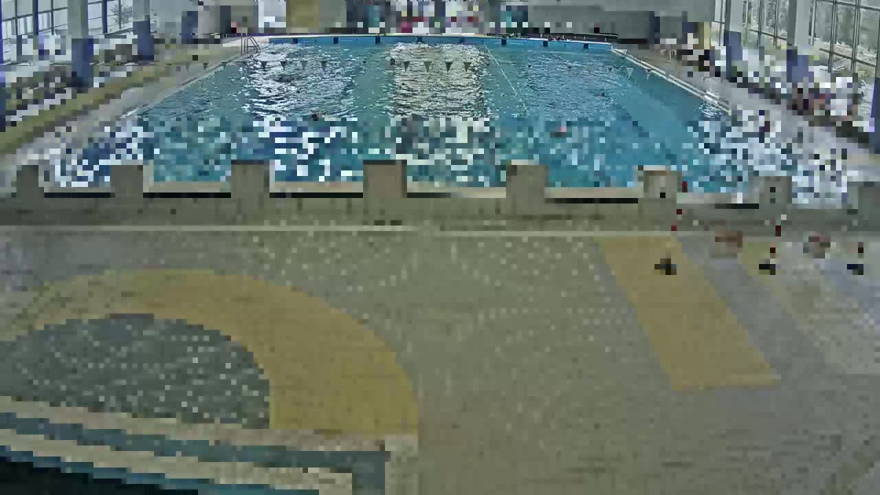 An indoor swimming pool with many people swimming in it.