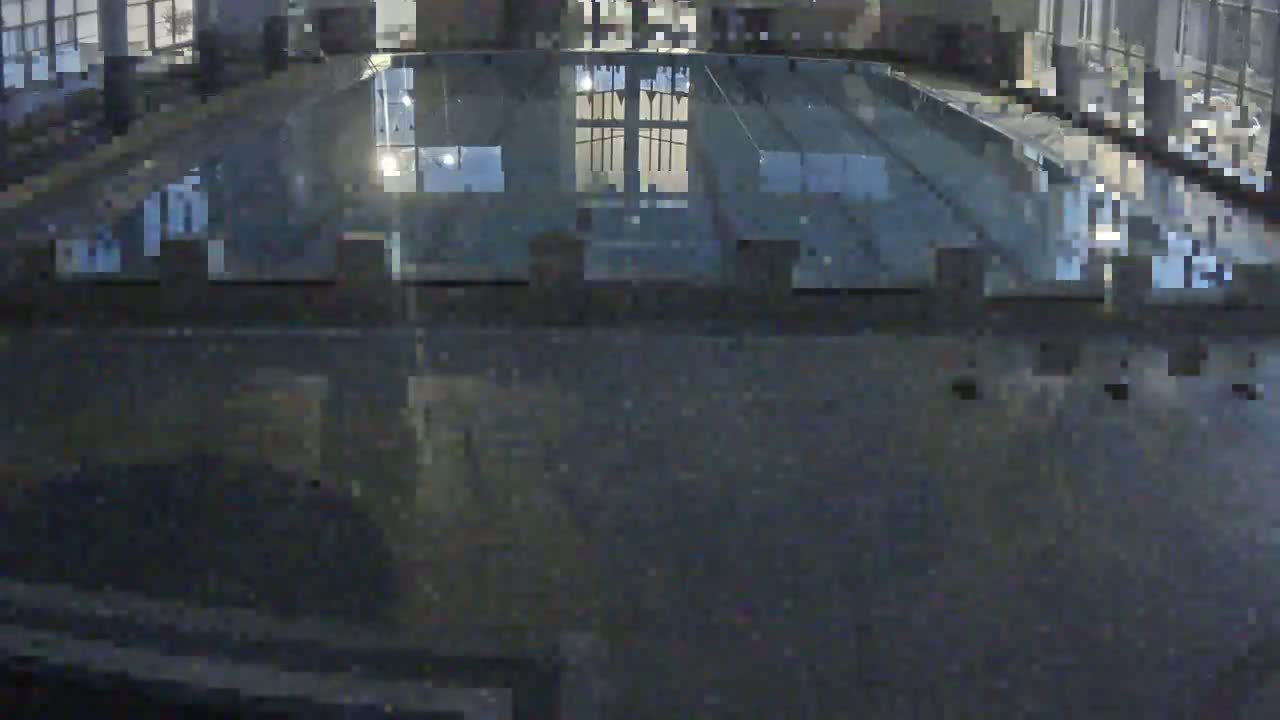A dark, possibly nighttime, view of a glass-covered structure reflecting interior lights.