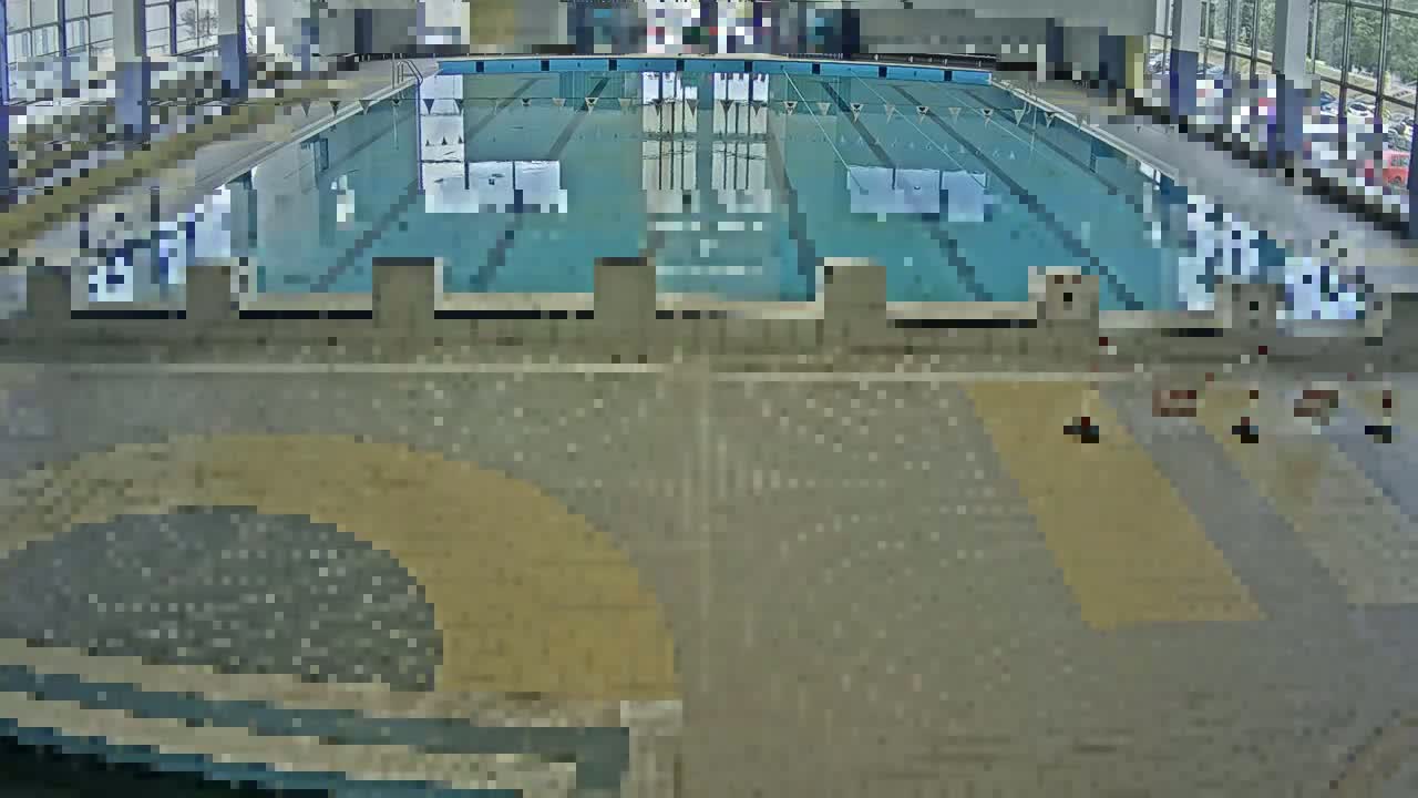 An indoor swimming pool with multiple lanes is viewed from above, the surrounding area showing a tiled floor.