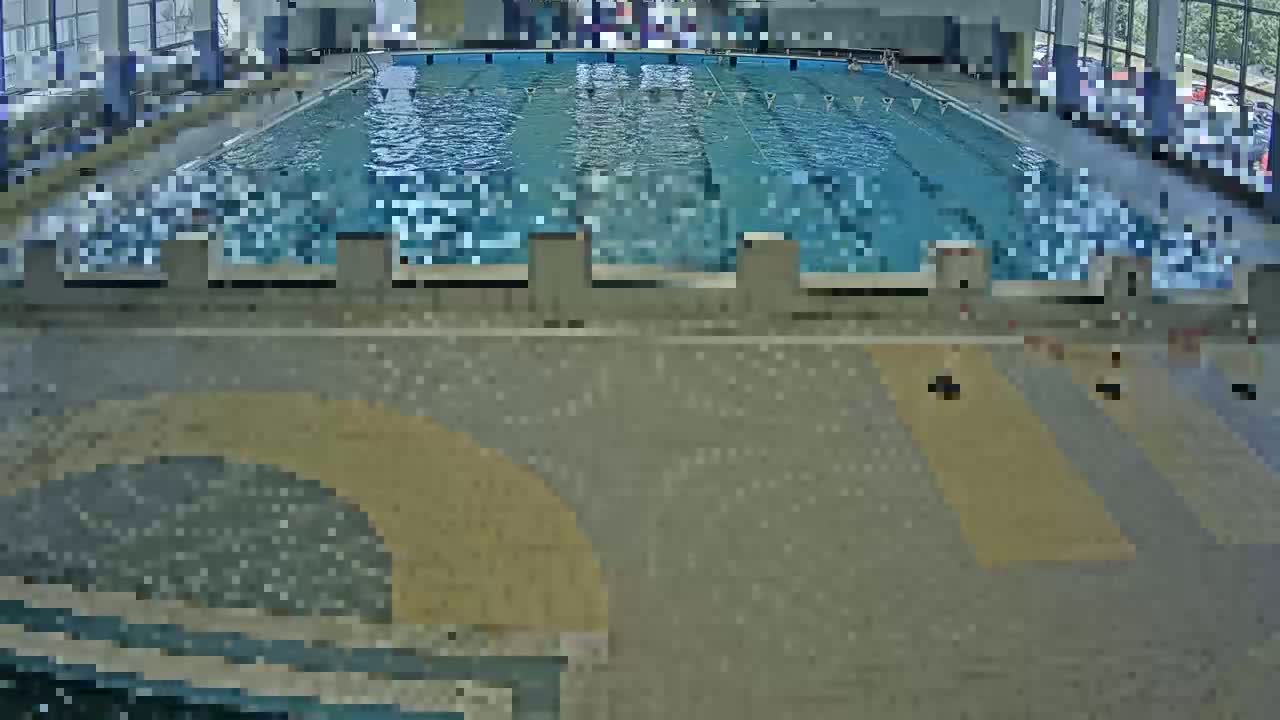 An indoor swimming pool with multiple lanes is shown, surrounded by a tiled floor.