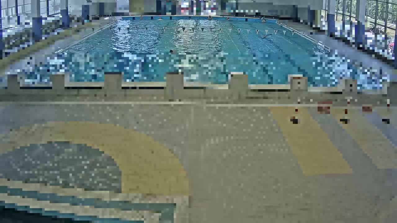 An indoor swimming pool with several people swimming in it.