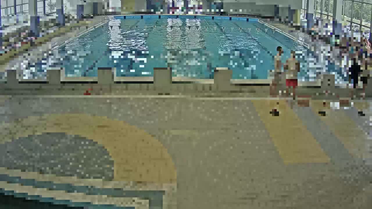 An indoor swimming pool with people swimming and standing around the edges.