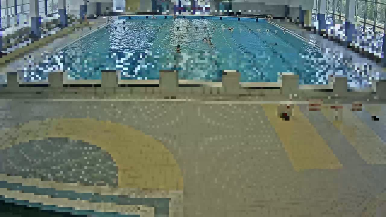An indoor swimming pool with several people swimming in it.