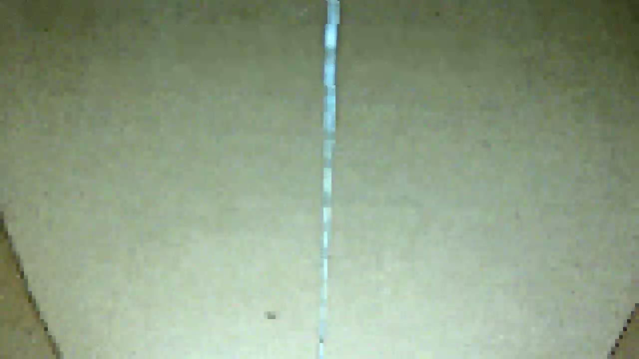 A thin, white stream flows down a light beige surface.