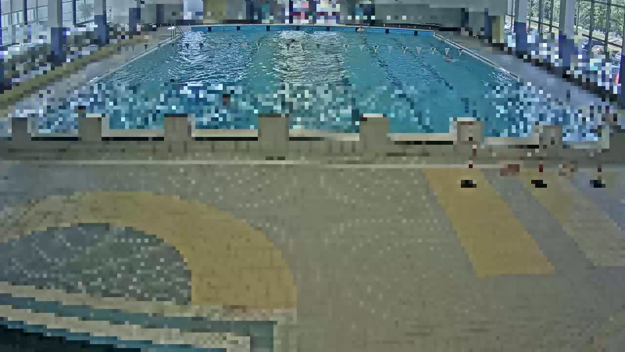 An indoor swimming pool with numerous people swimming in it.