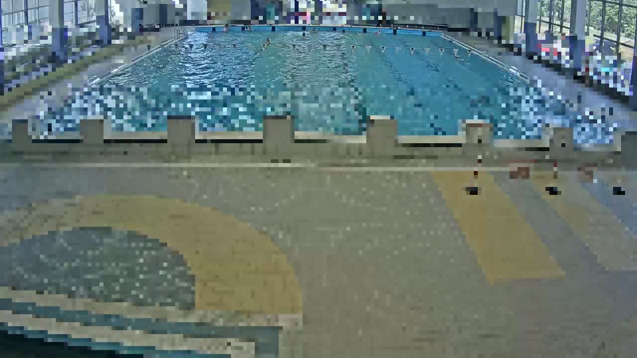 An indoor swimming pool with several people swimming in it.