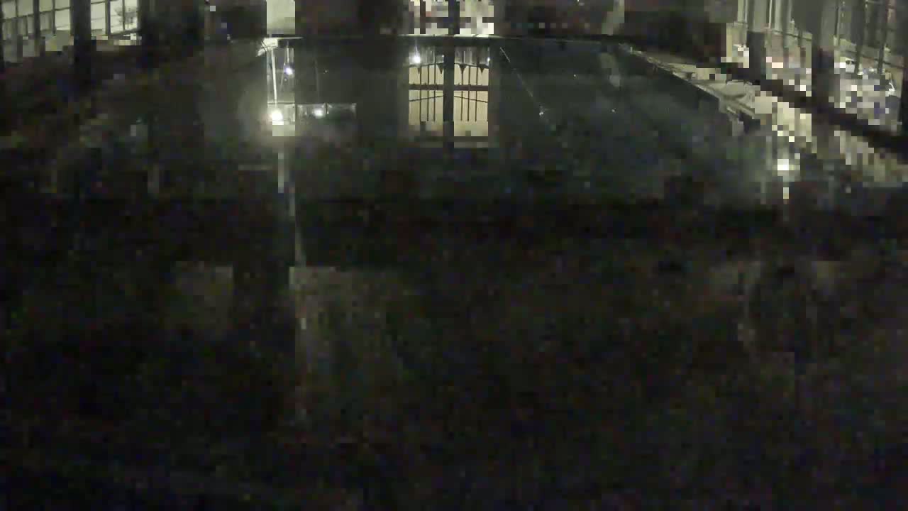 An indoor swimming pool with a light-grey tiled floor and several lane dividers is seen from an elevated vantage point.