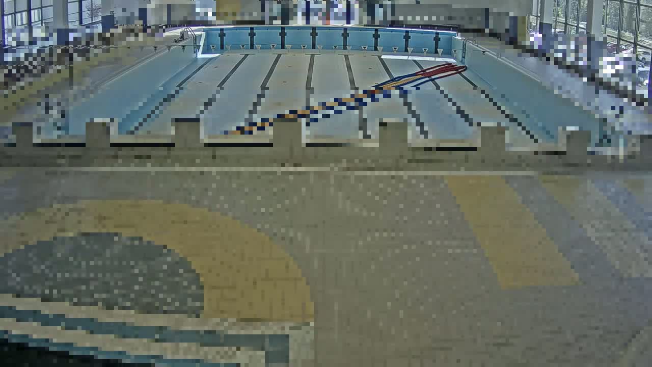 An indoor swimming pool with multiple lanes and a dividing line is shown from an overhead perspective.