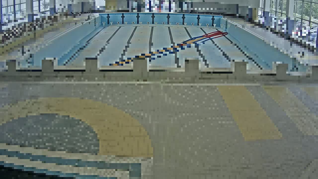 An indoor swimming pool with multiple lanes and starting blocks is viewed from above.