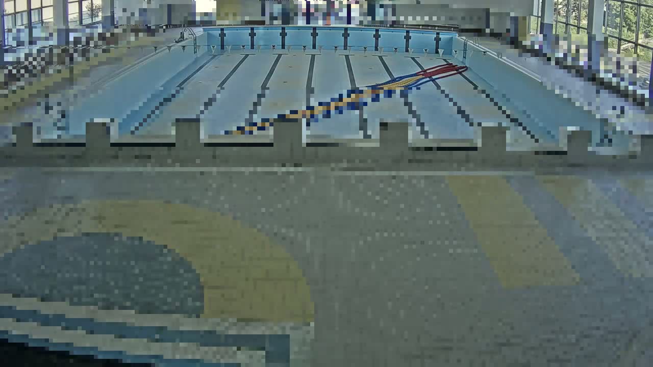 An indoor swimming pool with multiple lanes and starting blocks is viewed from above.