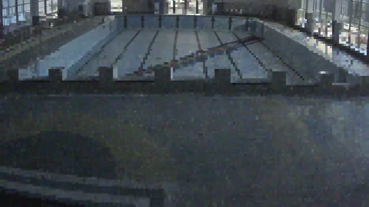 An indoor swimming pool viewed from above, showing empty lanes and a diving area.