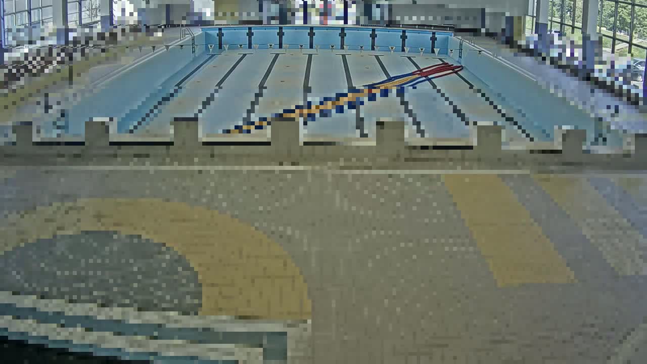 An indoor swimming pool with multiple lanes and starting blocks is viewed from above.