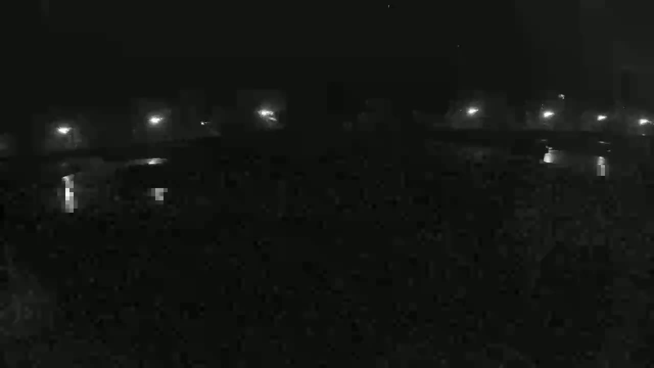 A nighttime view shows a dark expanse of land illuminated sparsely by distant lights.