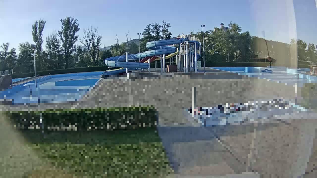 A view of an outdoor swimming pool complex with multiple water slides on a sunny day.