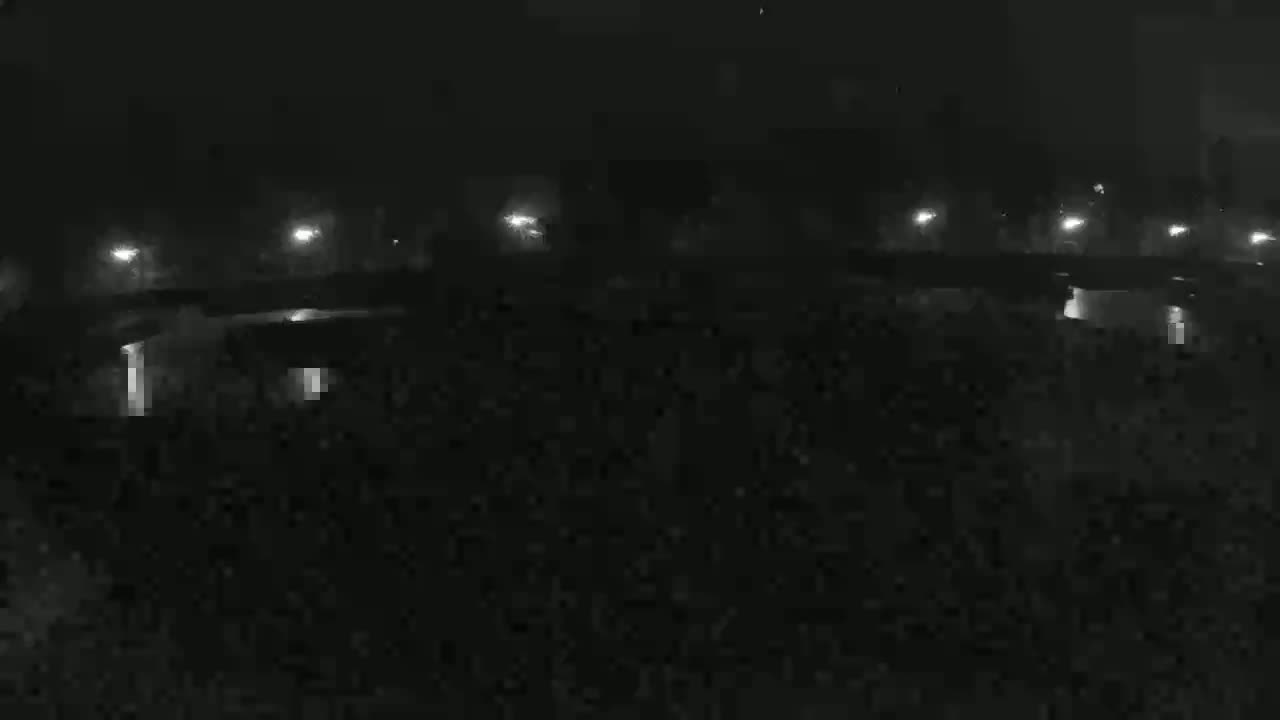 A nighttime, low-light view shows a dark roadway lit by distant lamps.