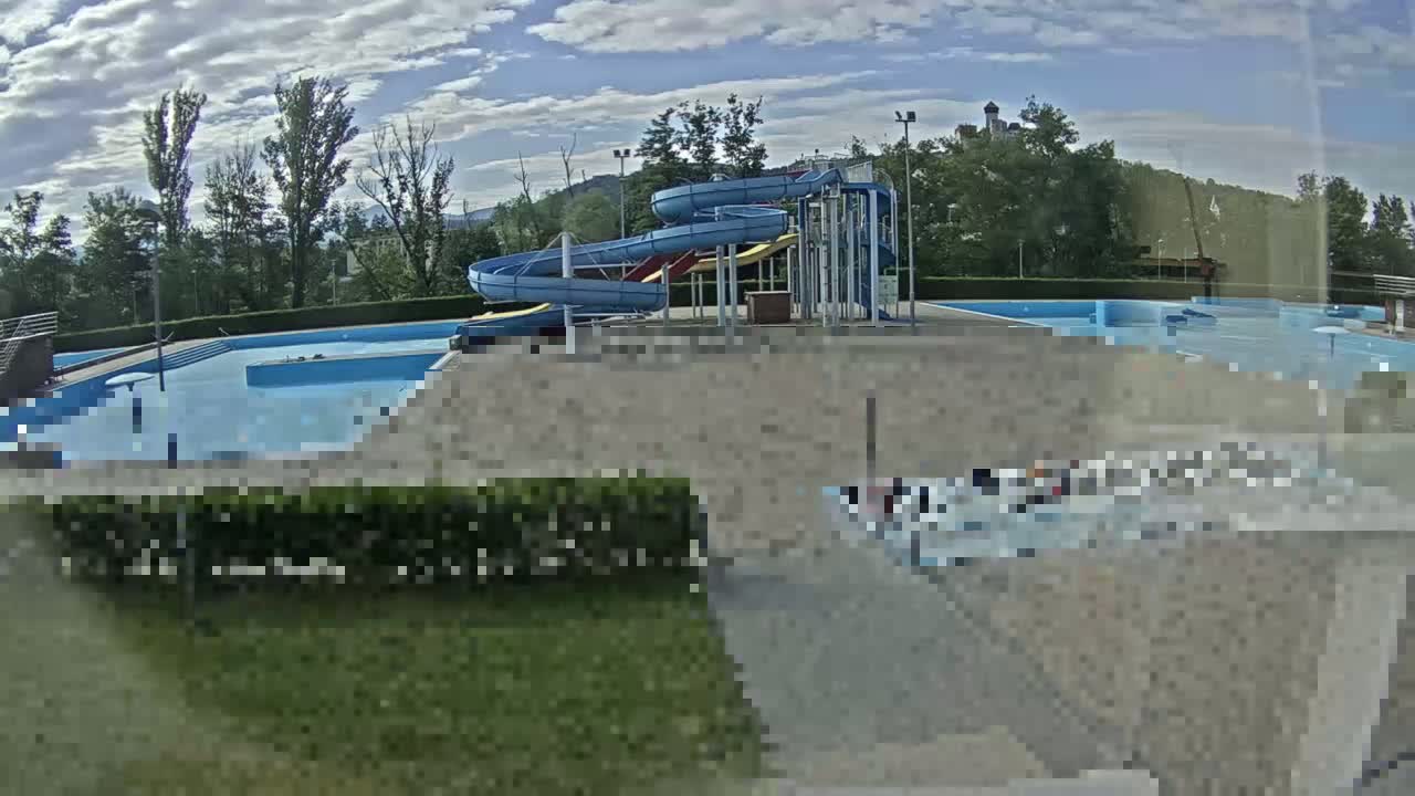 A swimming pool complex with multiple water slides sits under a partly cloudy sky.