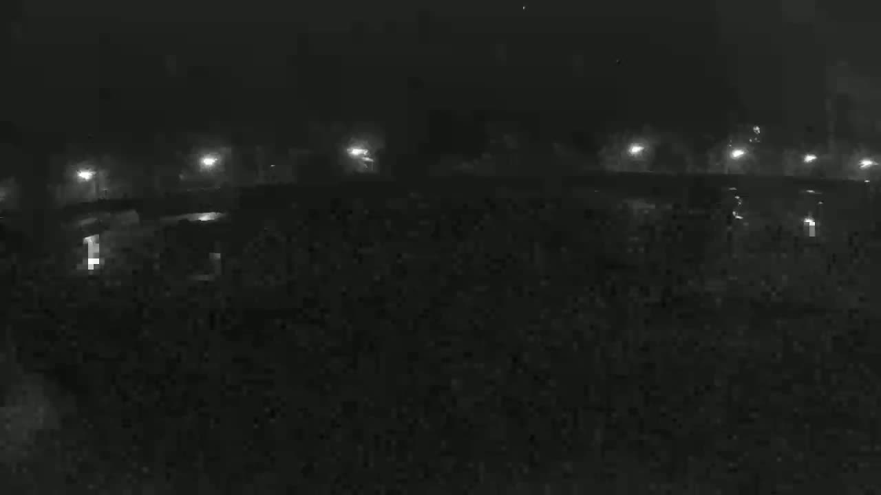 A nighttime, low-light view of a structure, possibly a bridge or overpass, illuminated by several distant lights.
