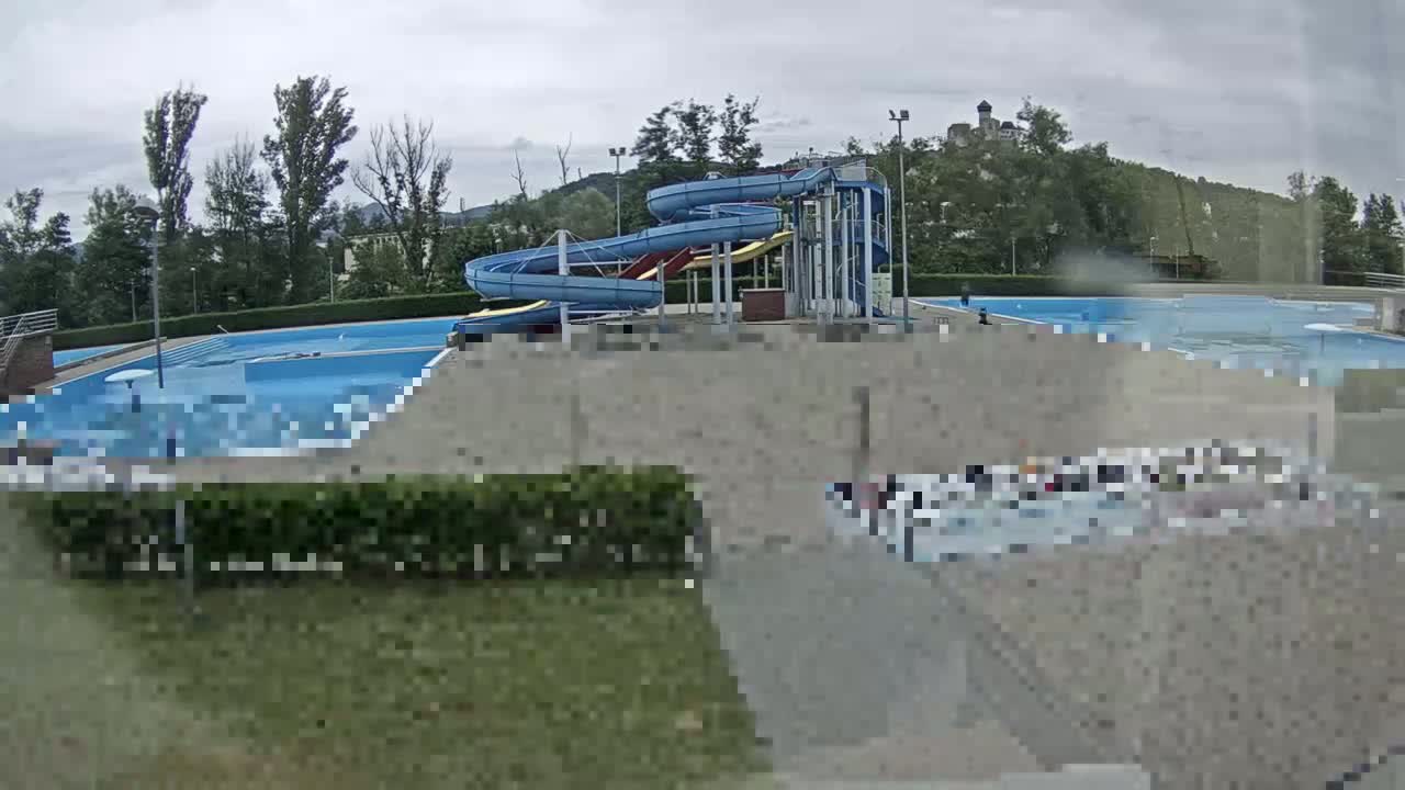 An outdoor swimming pool complex with water slides is visible under an overcast sky.