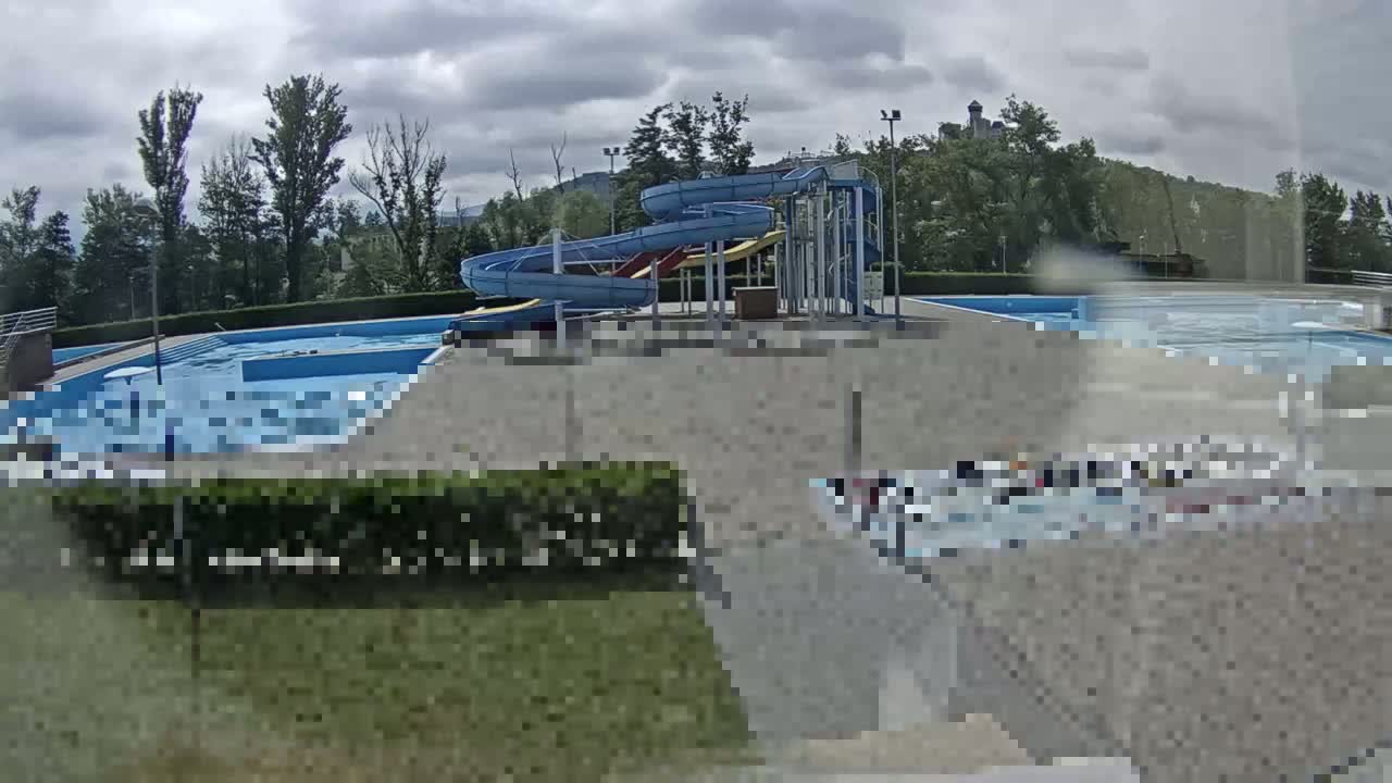 An outdoor pool complex with two twisting water slides is visible under a cloudy sky.