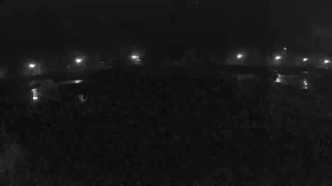 A nighttime, foggy view shows a dark landscape with faintly visible lights in the distance.