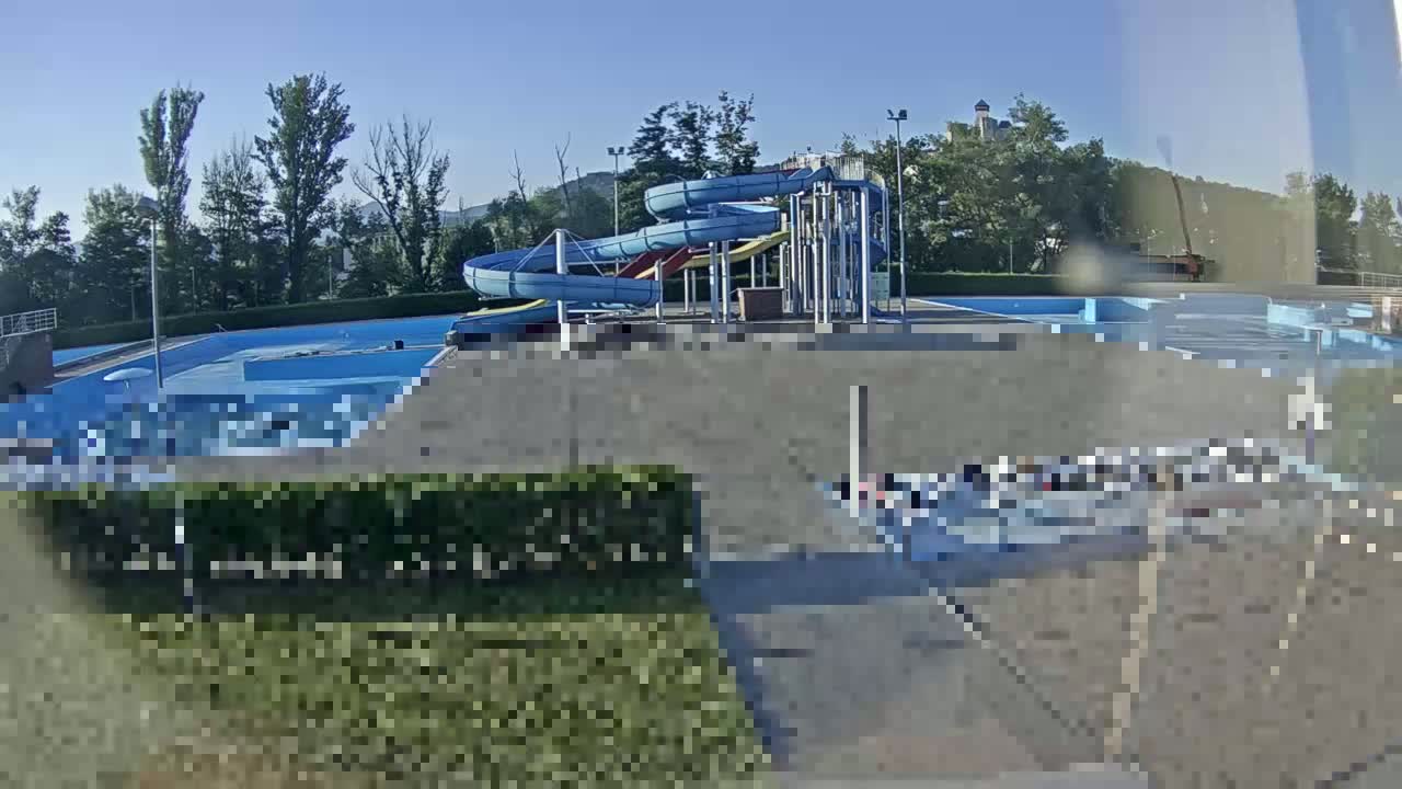 A water park with several blue water slides and a swimming pool is visible on a sunny day.