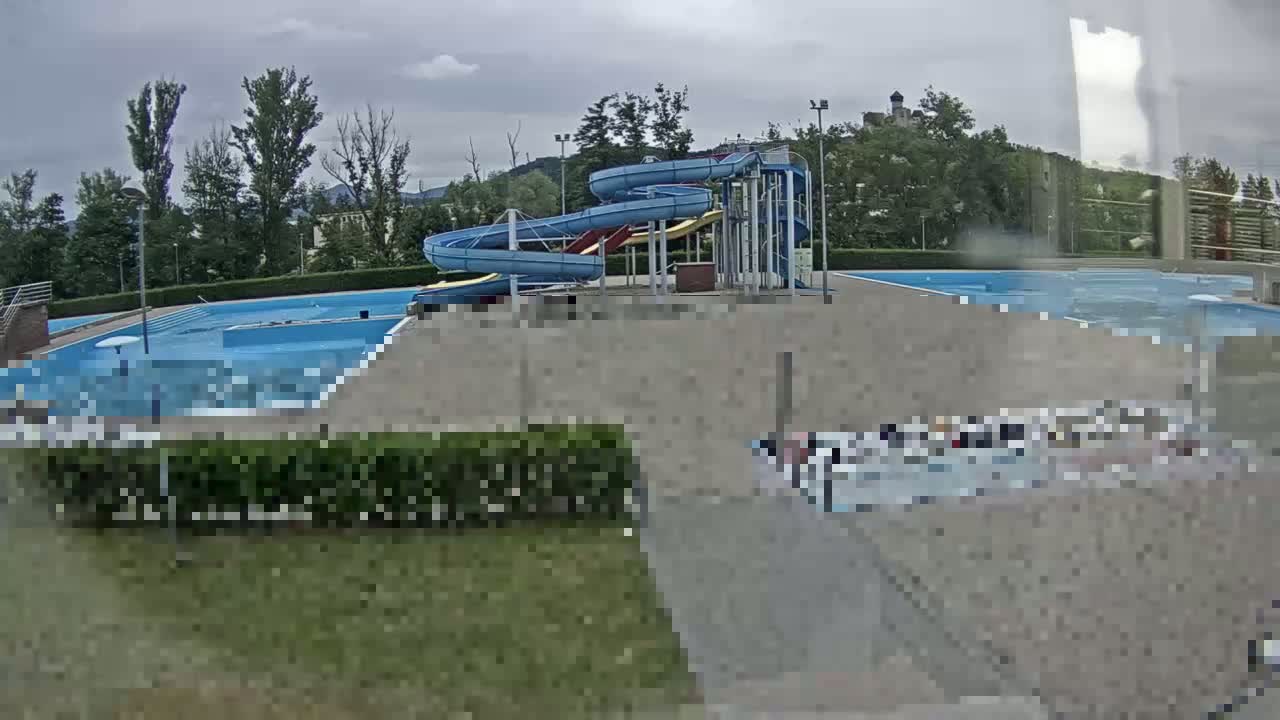 An outdoor swimming pool complex with water slides is visible under an overcast sky.