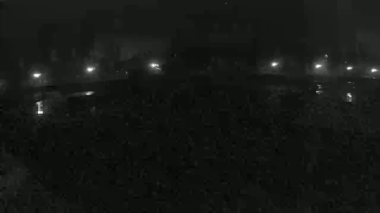 A dark, foggy night scene shows a row of lights in the distance, illuminating indistinct objects below.