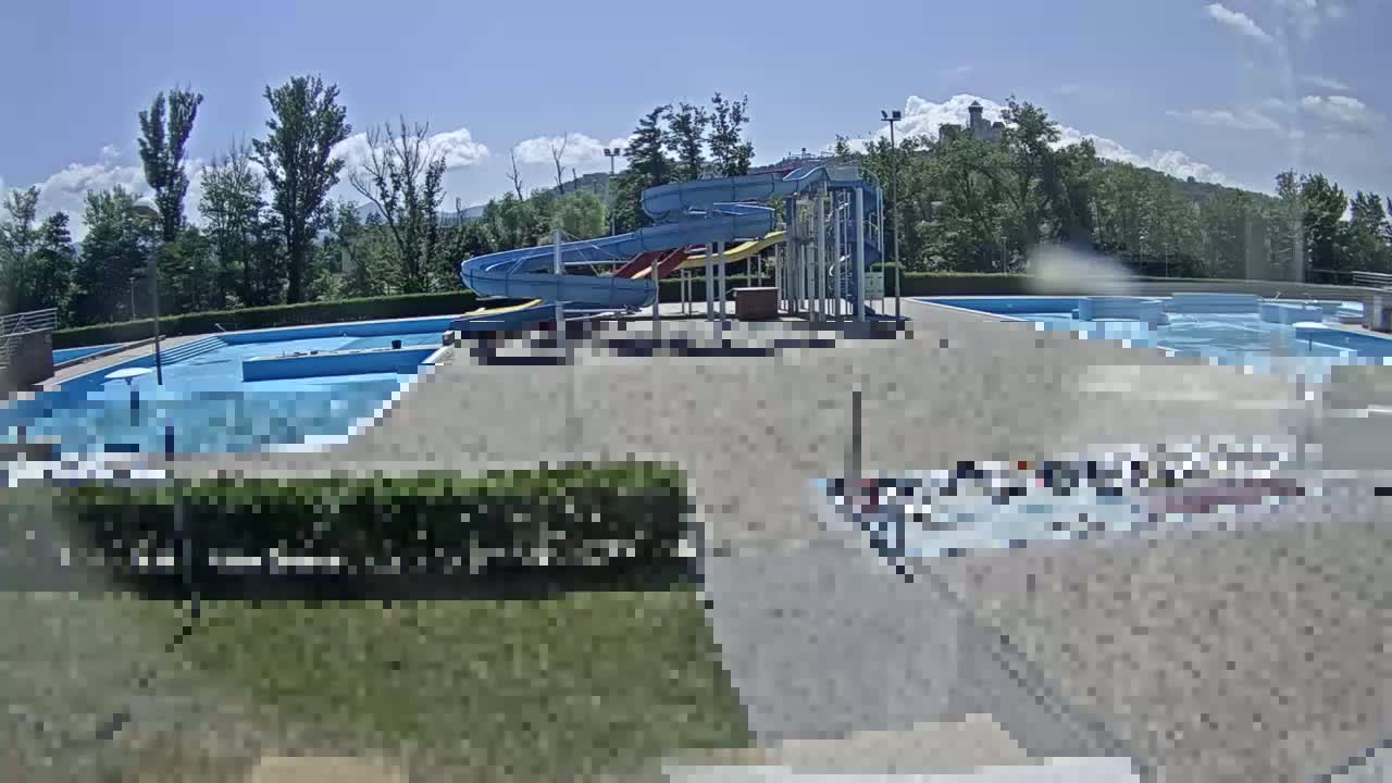 An outdoor water park with several pools and water slides is visible under a mostly sunny sky.