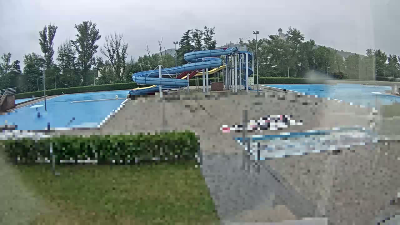 An outdoor swimming pool complex with water slides is seen on a cloudy, possibly rainy day.