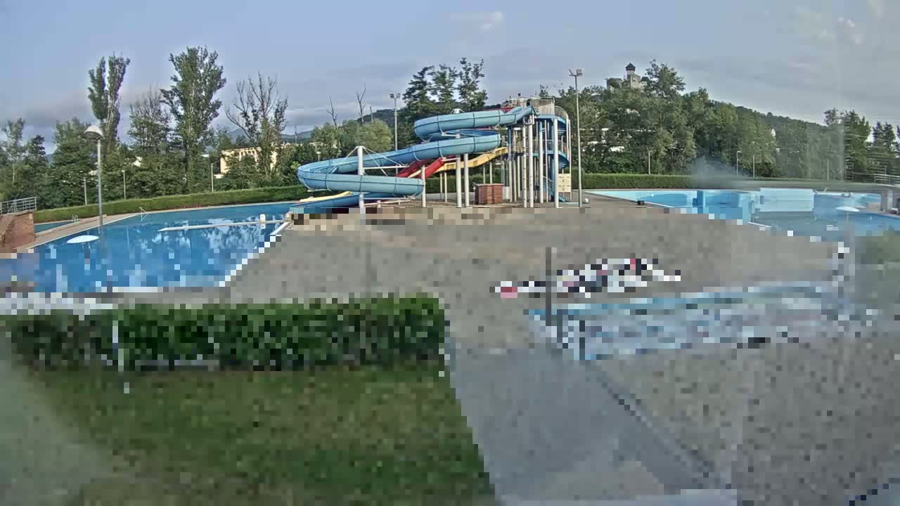 An outdoor swimming pool complex with several water slides is visible on a mostly clear day.