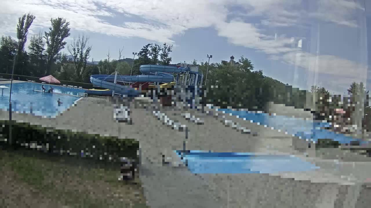 A water park with a swimming pool and water slides is visible under a partly cloudy sky.