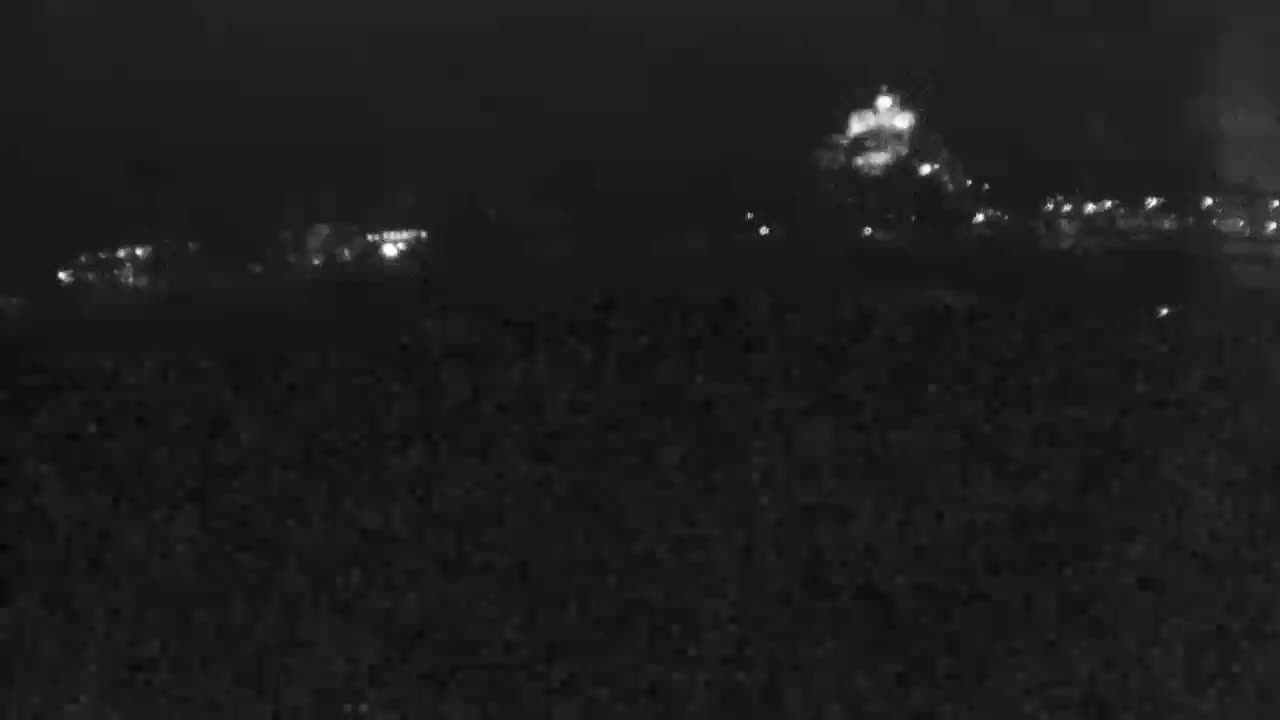 A blurry view through a window shows a swimming pool and surrounding area on a sunny day.