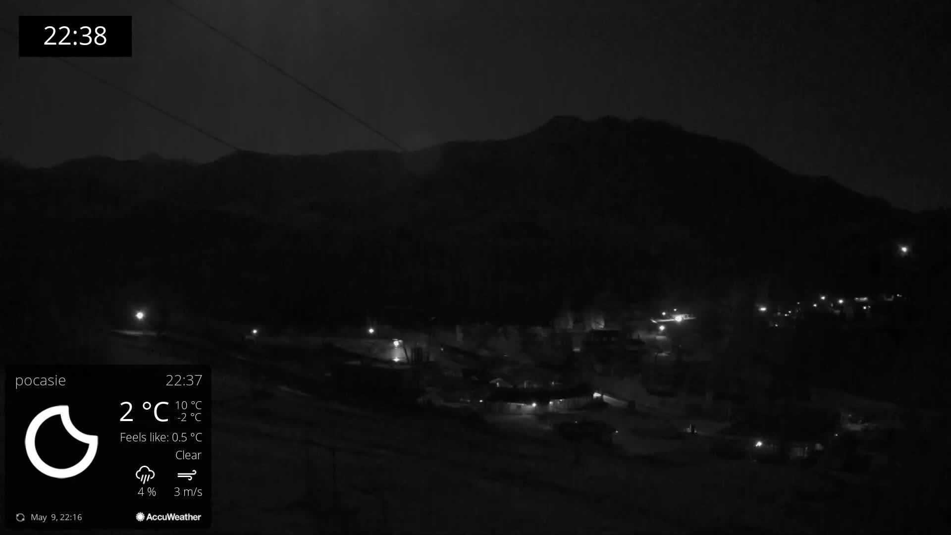 A nighttime, clear view of a snow-covered village nestled below a dark mountain range.