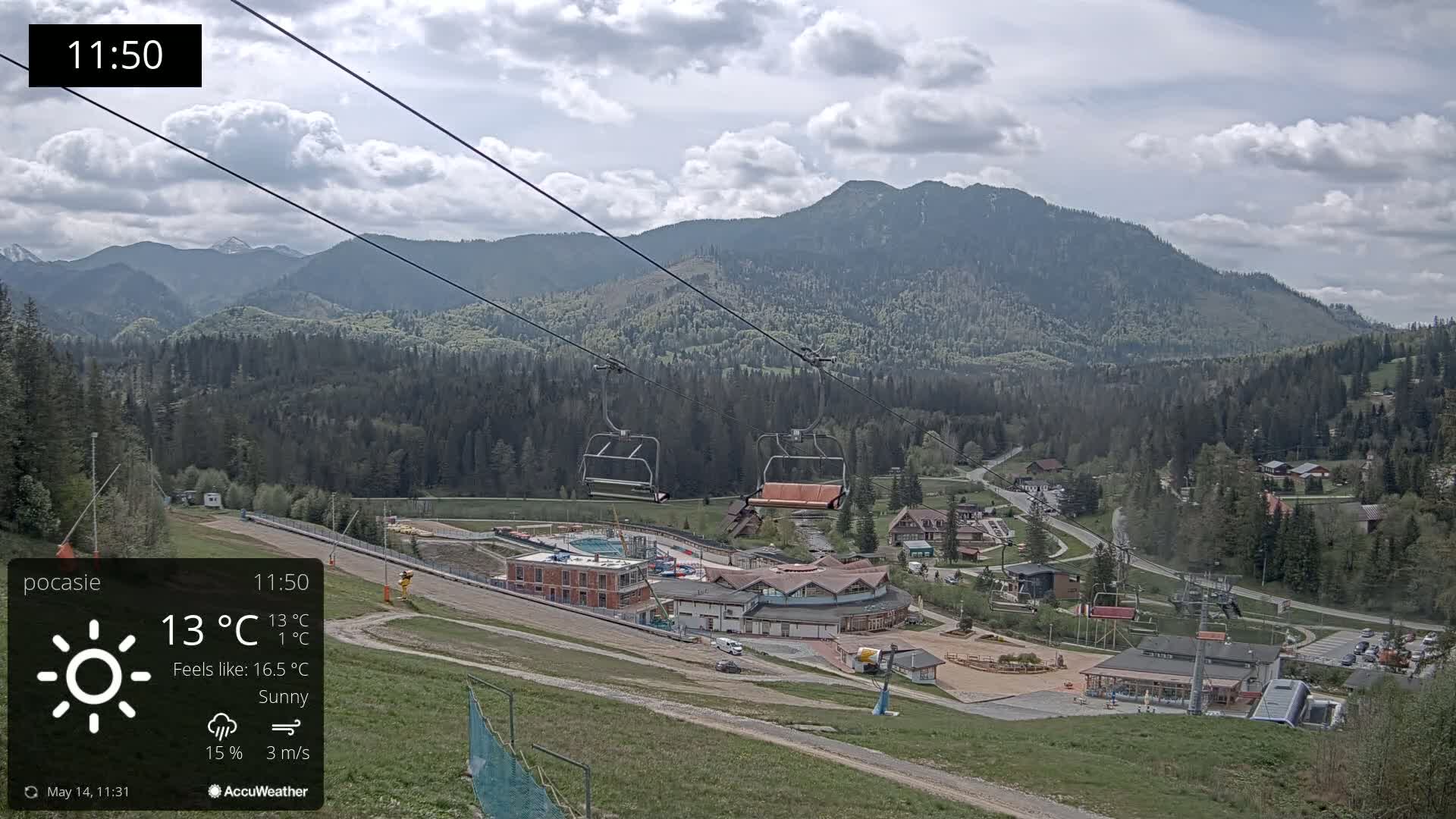 A sunny mountain resort with a chairlift and buildings is visible, nestled among green hills and forests under a partly cloudy sky.