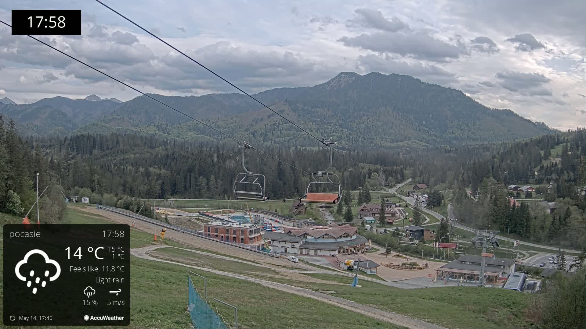 A mountain resort with a chairlift and light rain under a cloudy sky.