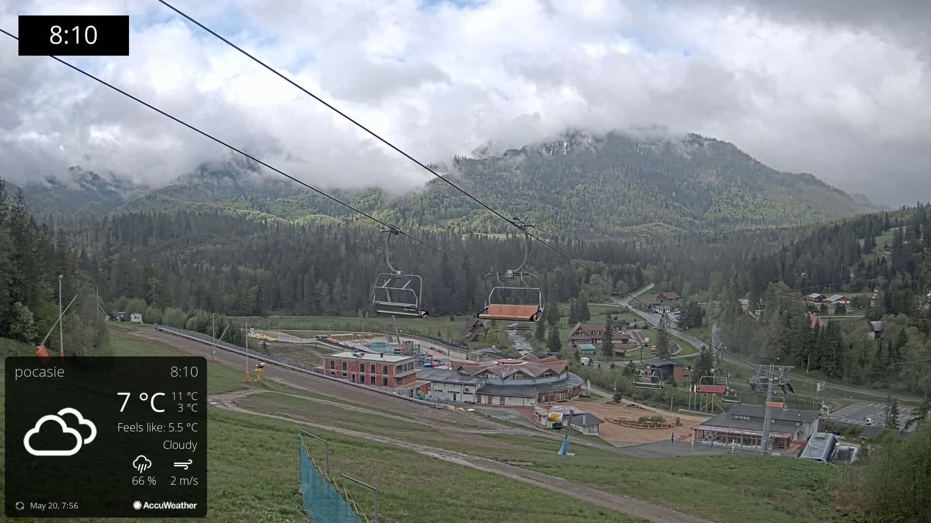 A cloudy, 7°C day shows a mountainside ski resort with empty chairlifts, and some buildings under a partially cloudy sky.