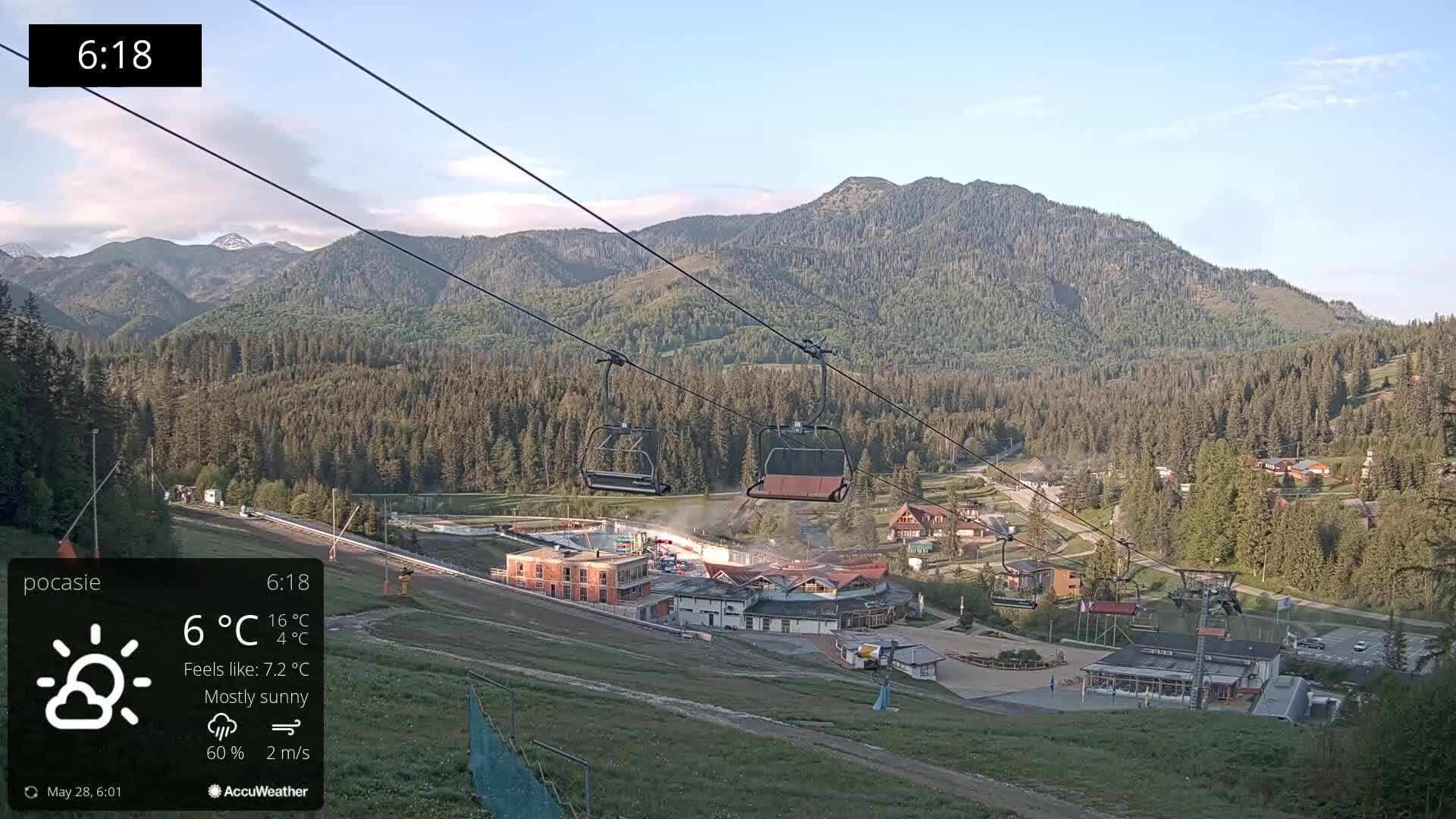 A mostly sunny mountainside ski resort with a chairlift and buildings is visible, under a light blue sky.
