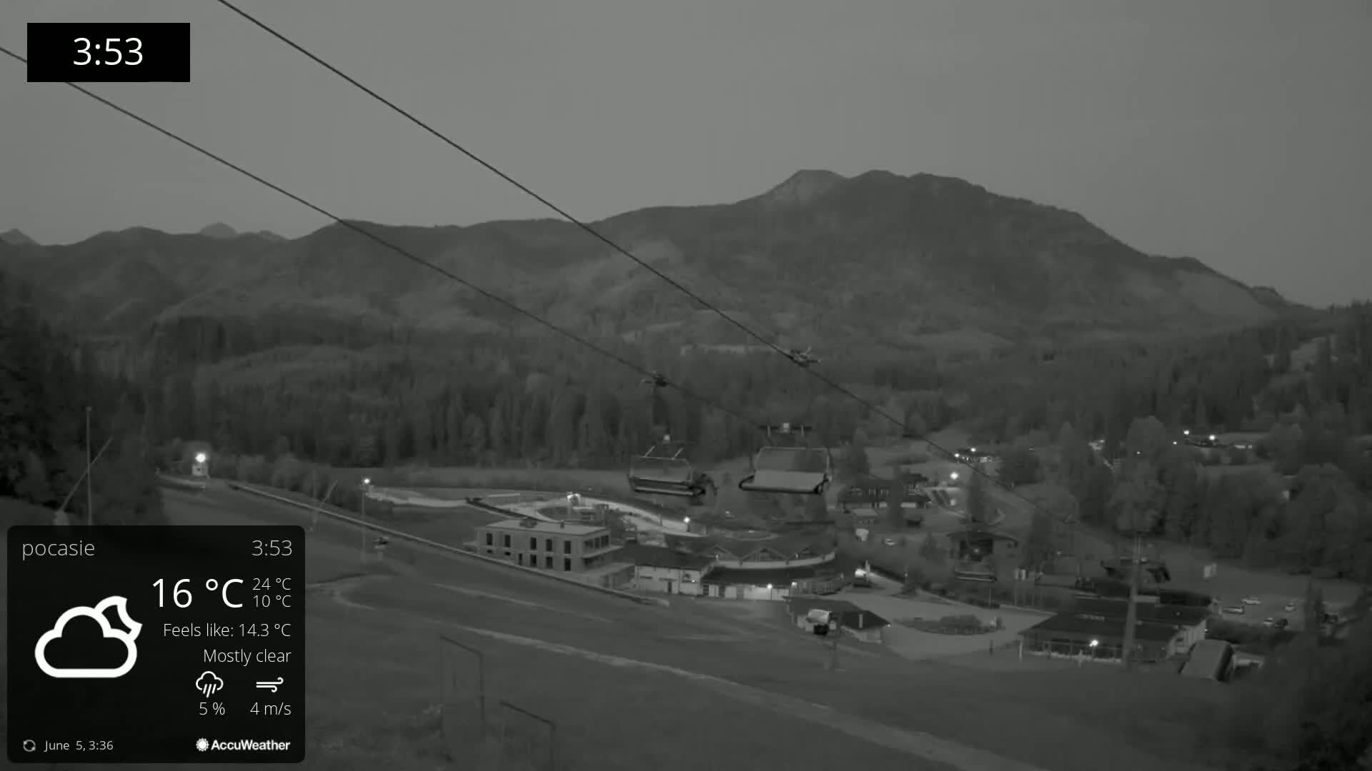 A mostly clear night scene shows a ski lift operating near a mountain under a twilight sky.