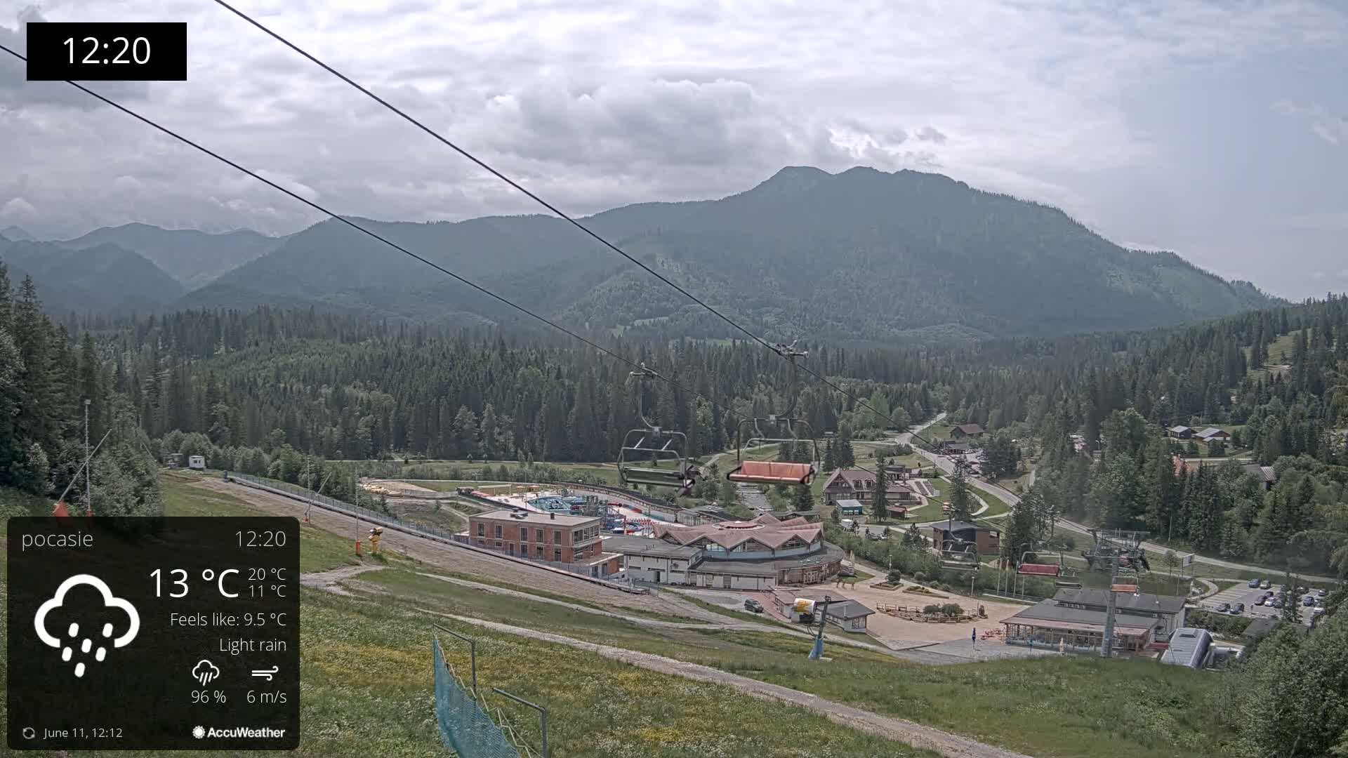 A mountain resort with a chairlift and light rain under a cloudy sky.