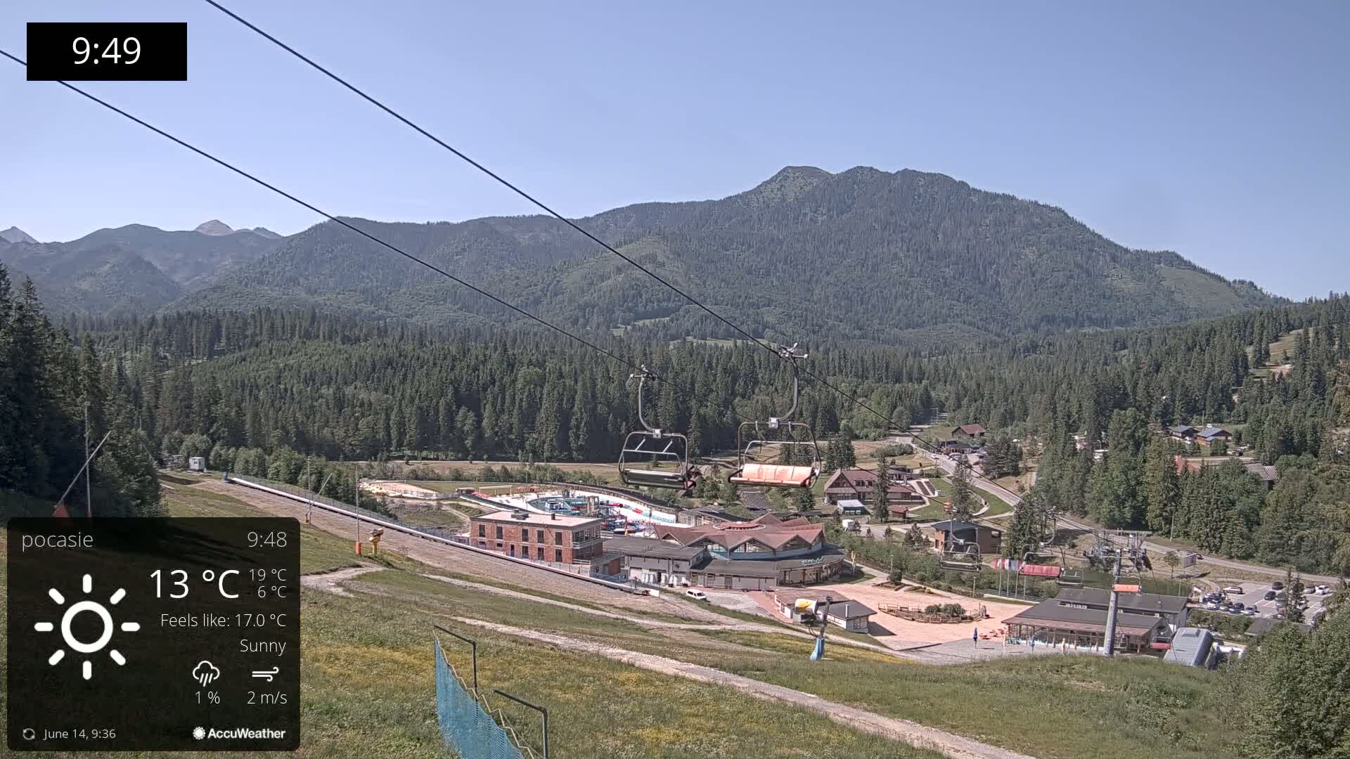 A sunny mountain resort with a chairlift and buildings is visible under a clear blue sky.