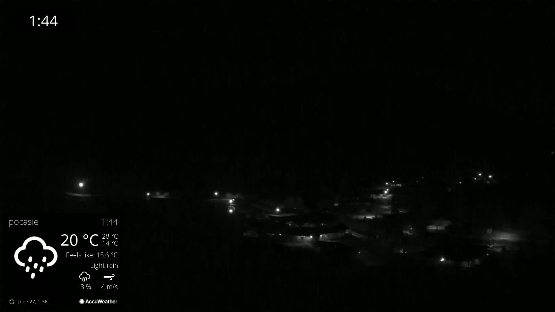 A mostly clear evening view shows a ski resort nestled in a valley surrounded by mountains, with chairlifts visible and a light breeze.
