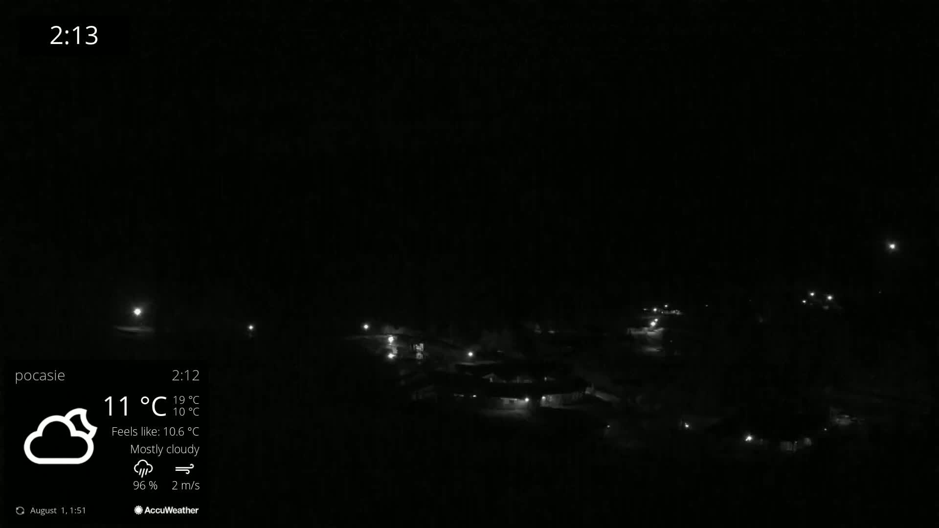 A mostly cloudy night scene shows dimly lit buildings and scattered lights.