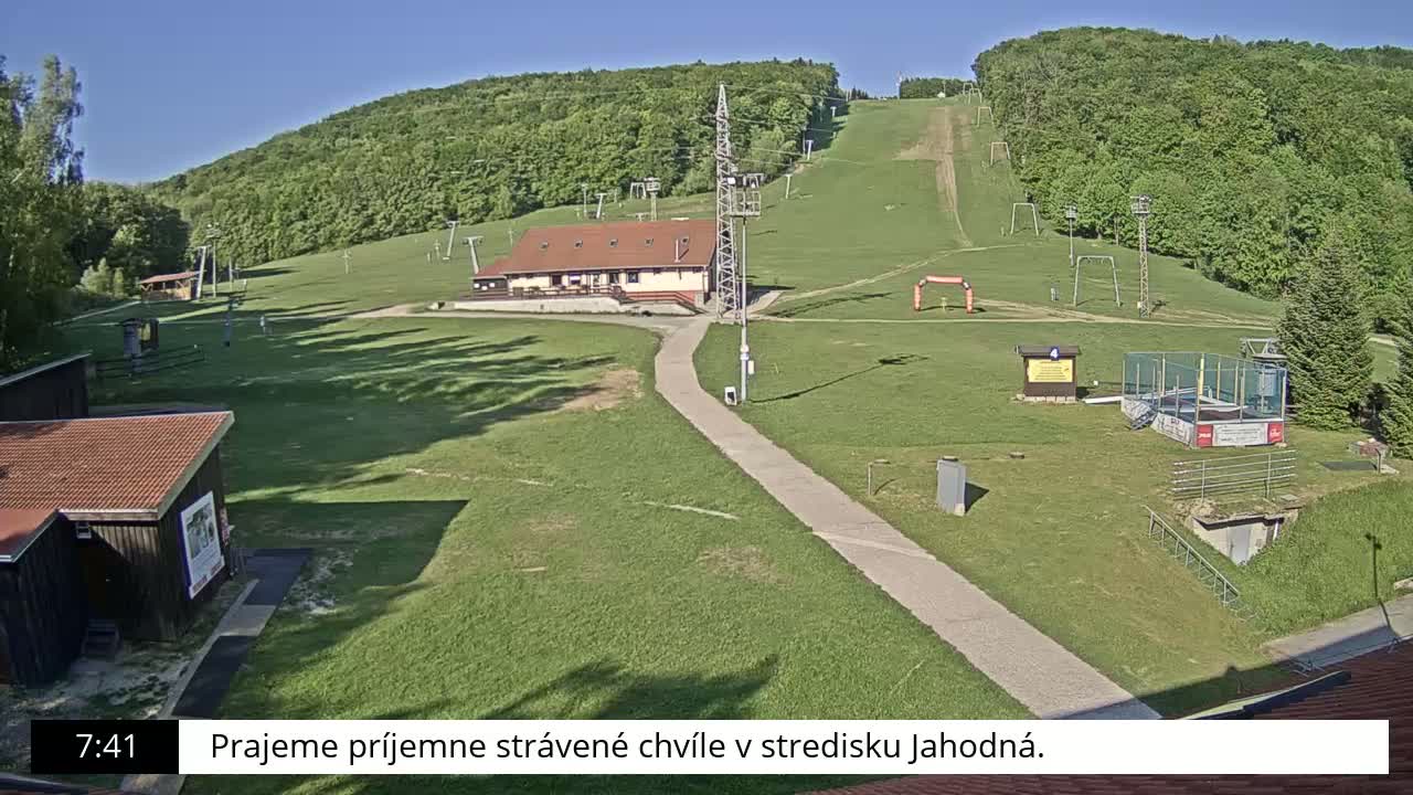 A ski slope with a building and other structures is visible on a sunny day.