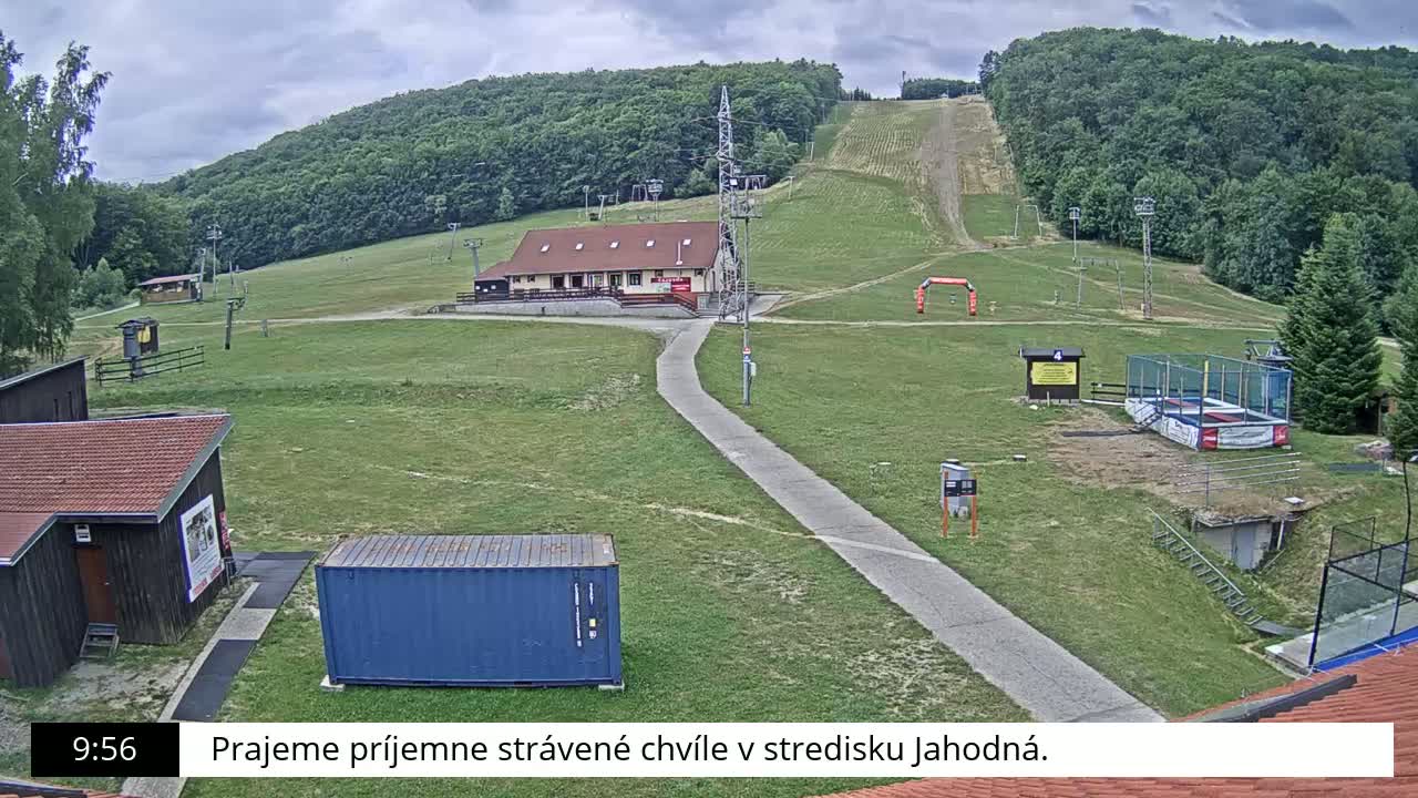 A ski slope with a building and several other structures is visible under an overcast sky.