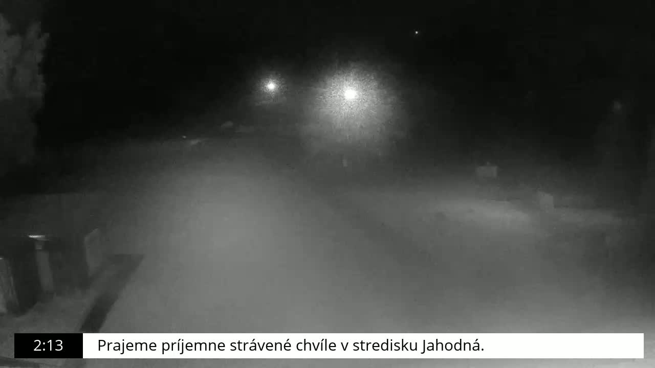 A nighttime, snowy scene is dimly lit by several distant lights.