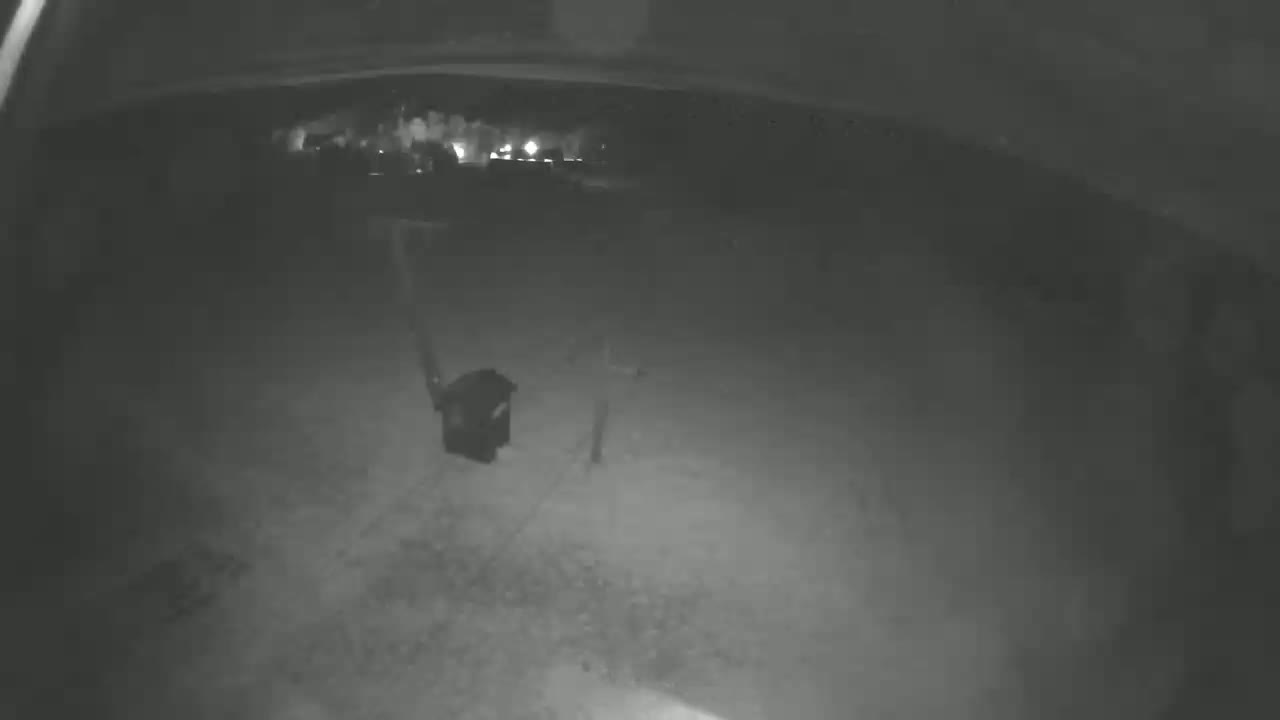 A nighttime, low-light view shows a dark, empty space with a dark object resembling a container in the center.