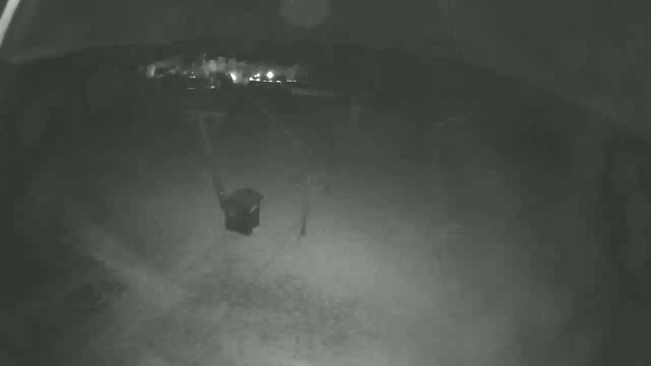 A nighttime, low-light view shows a dark, indistinct outdoor area with a dark rectangular object near the center.